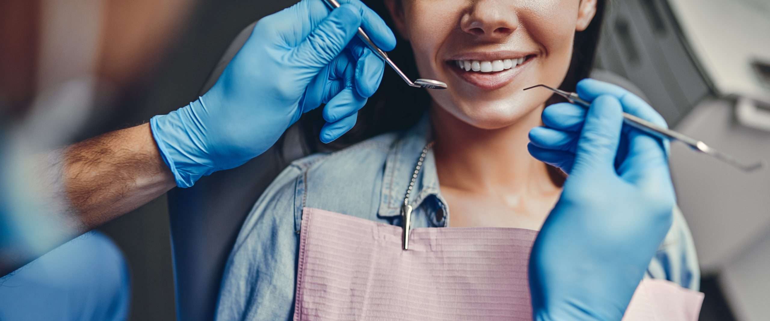 Dentist holding utensils up to woman's smiling mouth